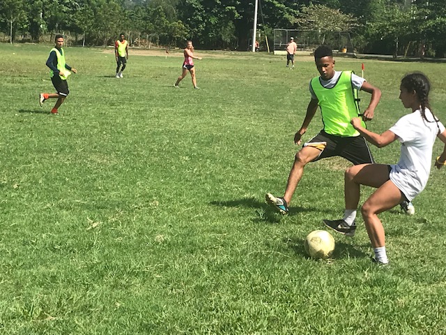 Young adults and children play soccer.