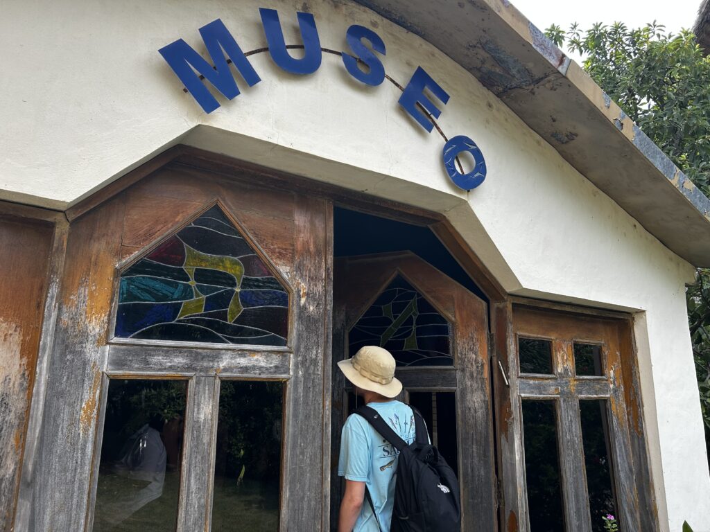 White building with stained wood doors that reads "Museo".