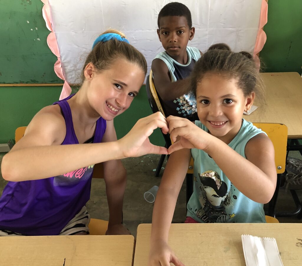 Two girls hold their hands together as hearts.