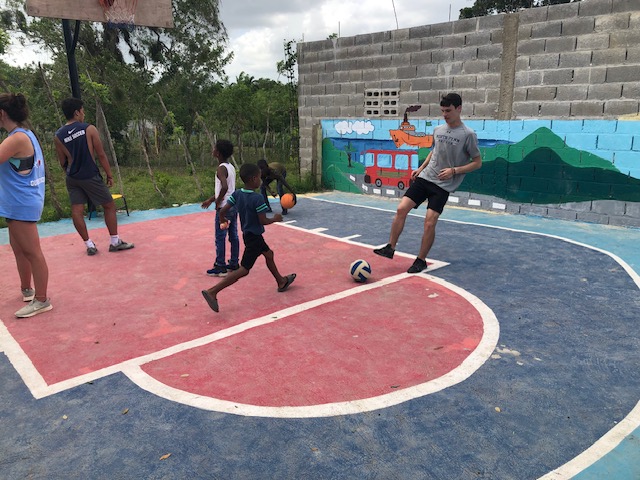 Young adults and children play with a variety of balls.