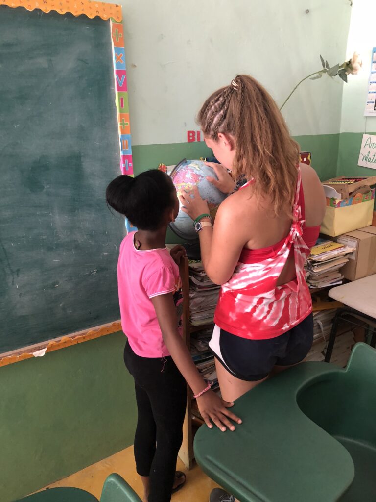 A young adult and a child study a globe.