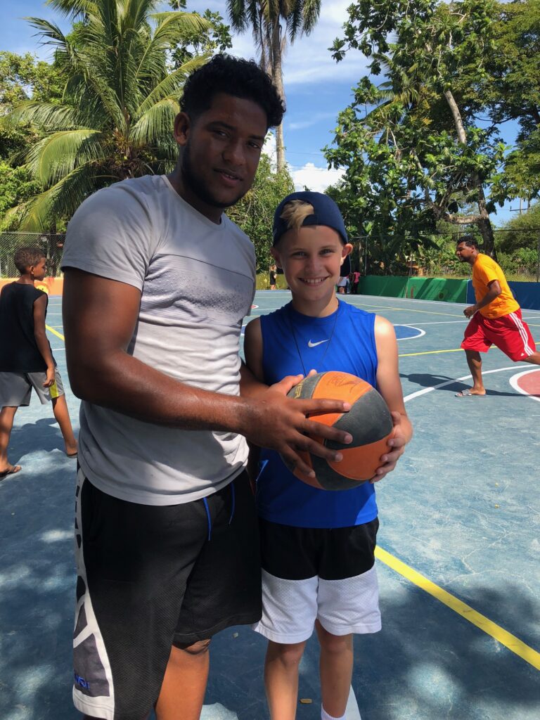A young adult and a child pose with a basketball.