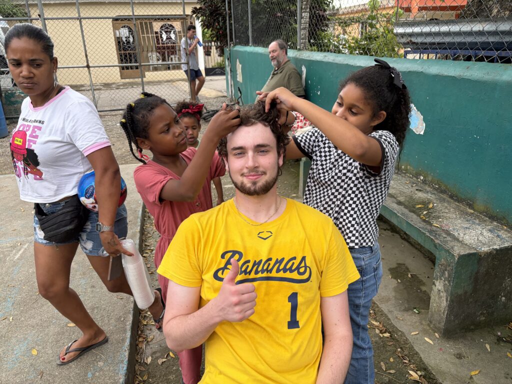 Children play with the hair of a male teen.